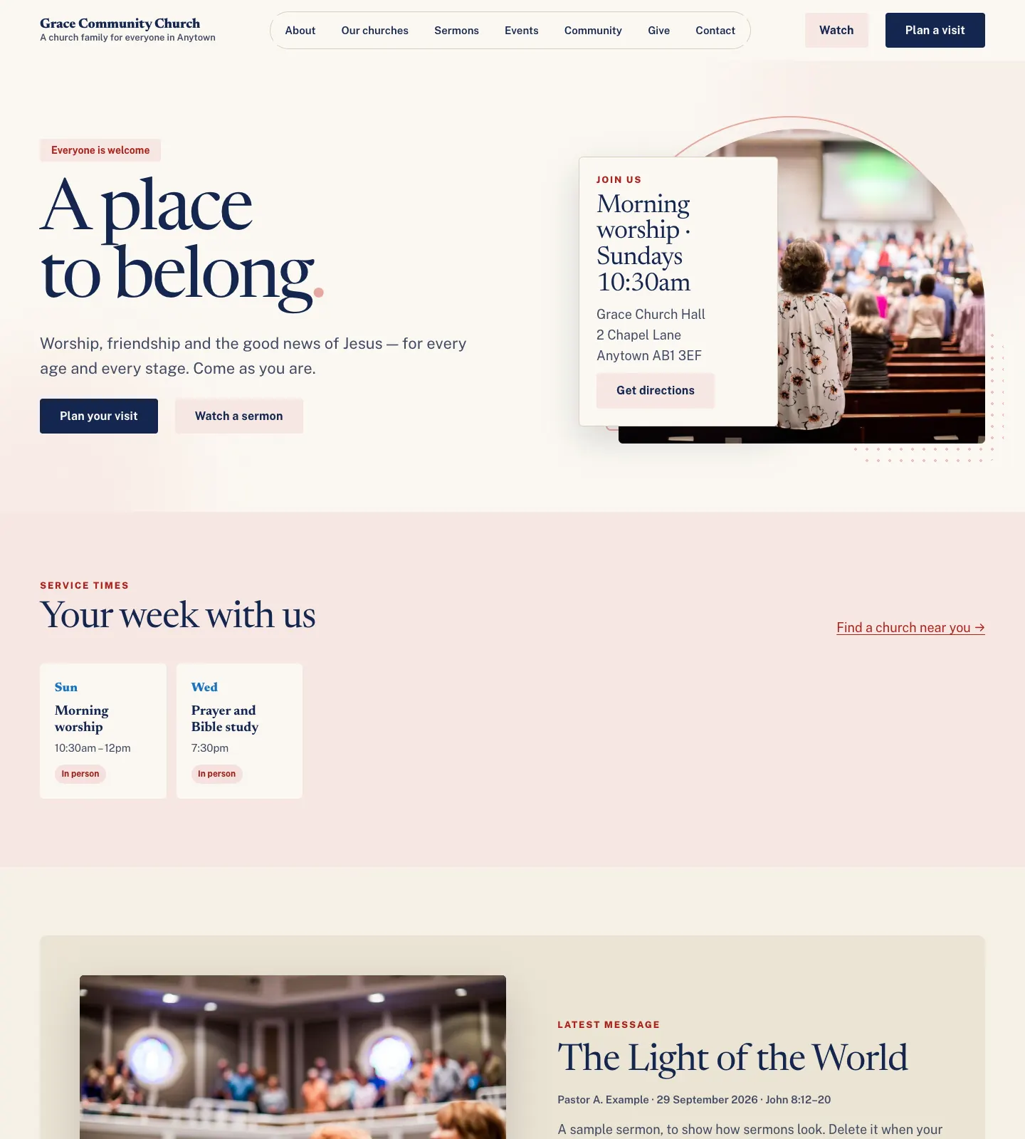 The Heritage design's home page: cream background, the serif headline "A place to belong." in navy, square navy and pale red buttons, red small headings and the service times on a pale pink band